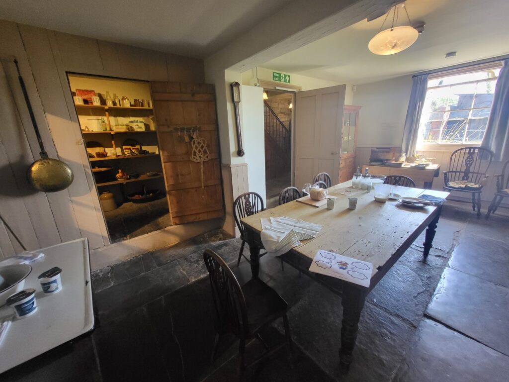 Farmhouse kitchen inside the Somerset Rural Life Museum, showing traditional utensils, fireplace, and rustic table