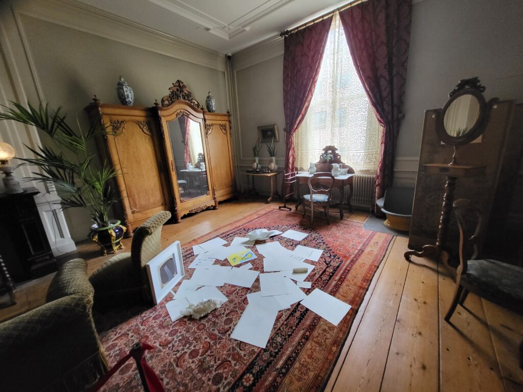 Art installation with scattered papers and floor photograph in historic room