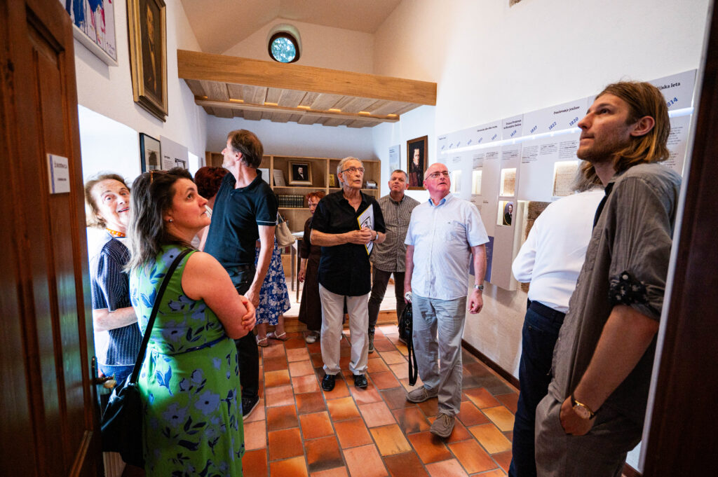 Andrej Jemec standing among visitors at his exhibition in Čop’s Birth House
