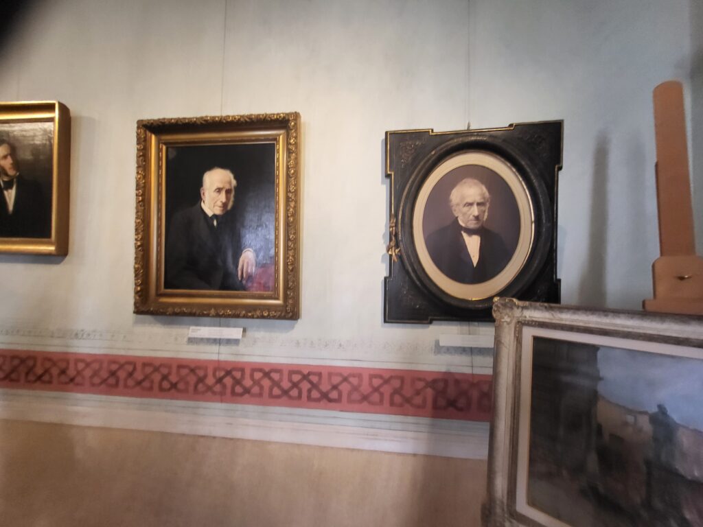 Portraits of Alessandro Manzoni including paintings and a photograph displayed on walls in Manzoni House Milan