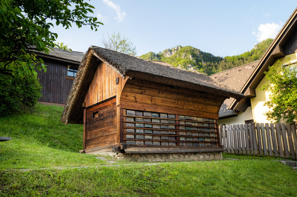 Janša’s Apiary in Breznica with thatched roof, painted beehive panels and grassy surroundings